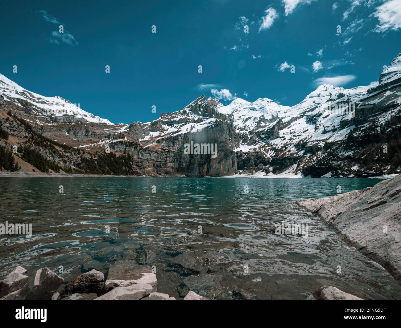 Alto lago alpino de Oeschinensee en Kandersteg, Suiza. El pintoresco lago azul claro está rodeado de altas montañas cubiertas de nieve, glaciares y Foto de stock