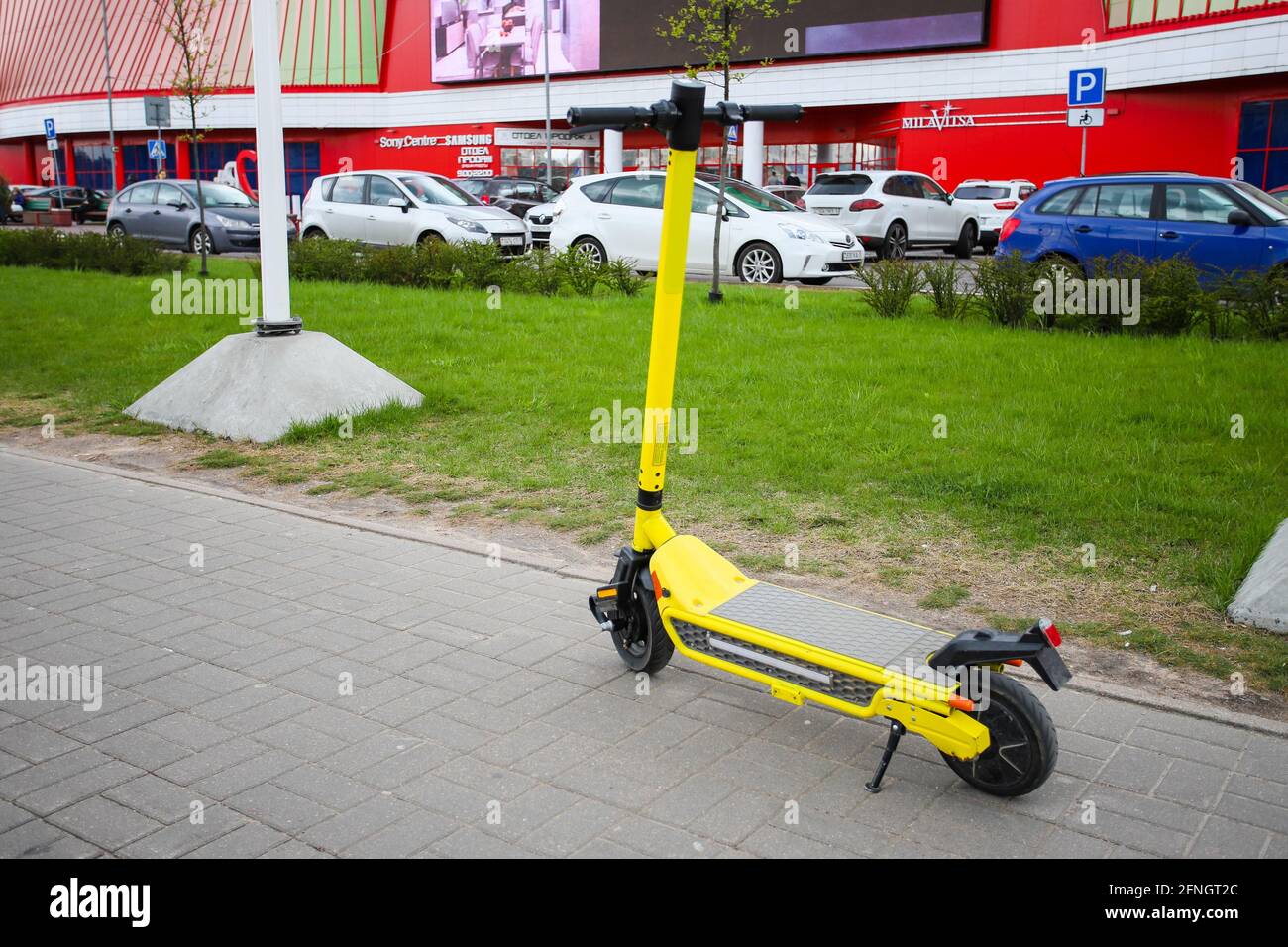 Minsk. BIELORRUSIA - MAYO 2021: Scooter eléctrico amarillo, alquiler de scooter en la ciudad. El scooter está frente a un centro comercial. Foto de stock