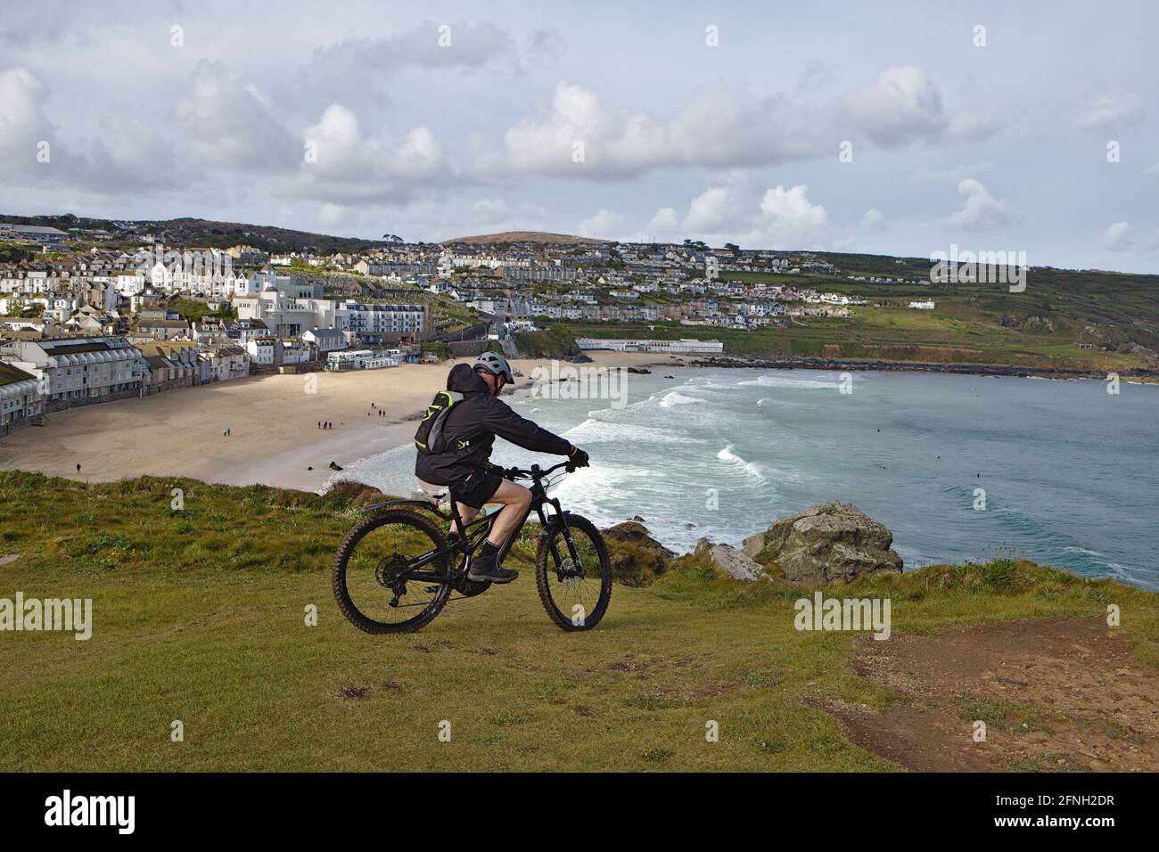 ciudadano de la tercera edad en bicicleta de montaña con vistas a la playa de porthmeor desde el isla st ives cornwall Foto de stock
