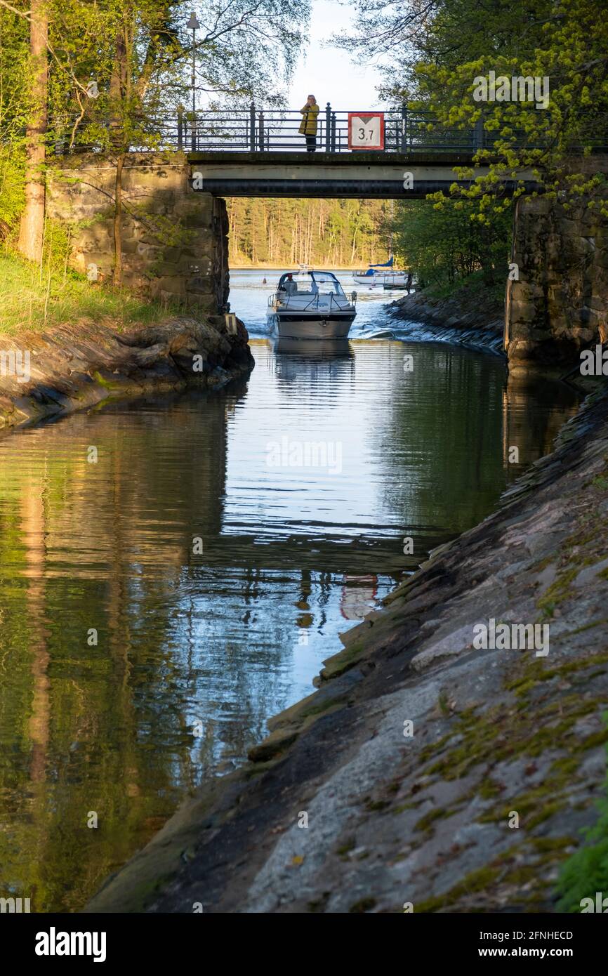 Helsinki / FINLANDIA - 16 DE MAYO de 2021: Un barco de ocio que viaja bajo el puente sobre un pequeño canal. Foto de stock