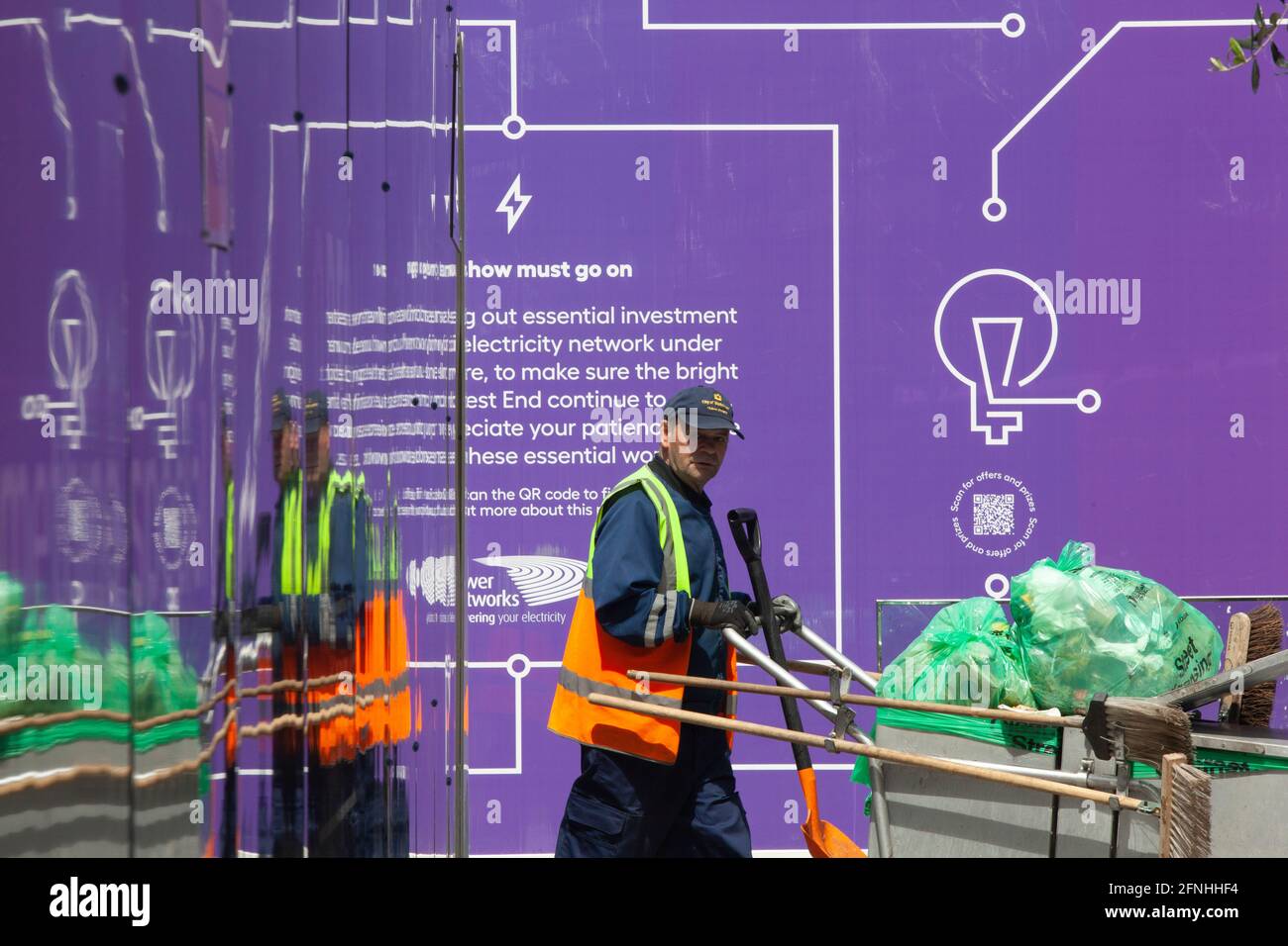 Londres, Reino Unido, 17 de mayo de 2021: El acaparamiento de un edificio refleja a los transeúntes, en este caso un limpiador de calles del consejo local, uno de los trabajadores clave que ha mantenido a Londres funcionando durante toda la pandemia. Anna Watson/Alamy Live News Foto de stock