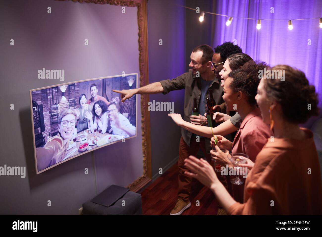 Un grupo diverso de jóvenes hablando a amigos en línea mientras disfrute de una fiesta en casa Foto de stock