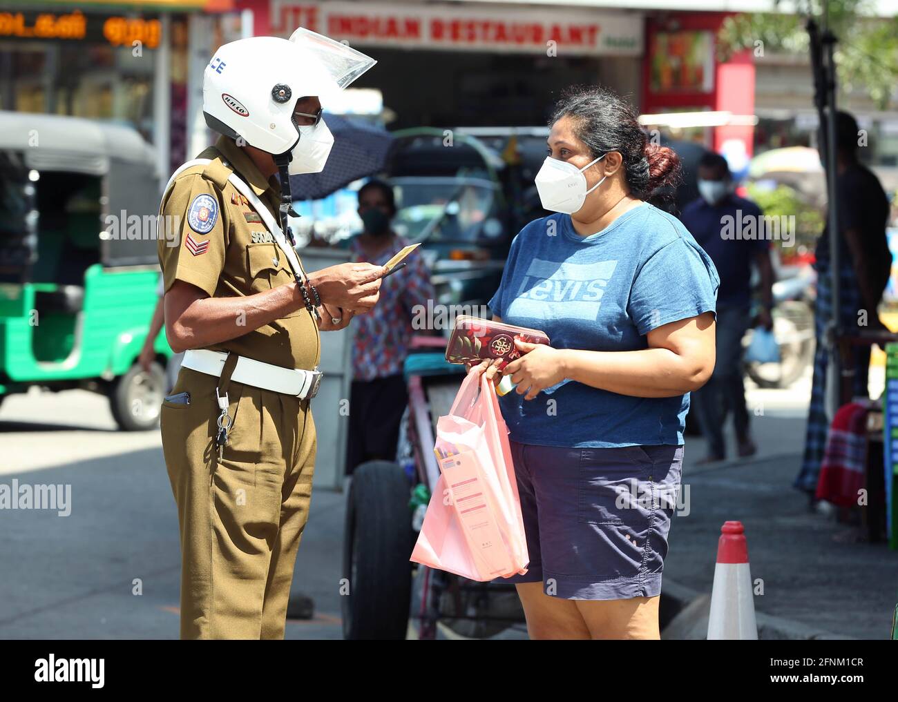 Colombo, Sri Lanka. 17th de mayo de 2021. Un oficial de policía comprueba las tarjetas de identificación a medida que las autoridades imponen un sistema de tarjetas de identificación para restringir la circulación de personas ante una tercera ola de COVID-19 en Colombo, Sri Lanka, 17 de mayo de 2021. Crédito: Ajith Perera/Xinhua/Alamy Live News Foto de stock