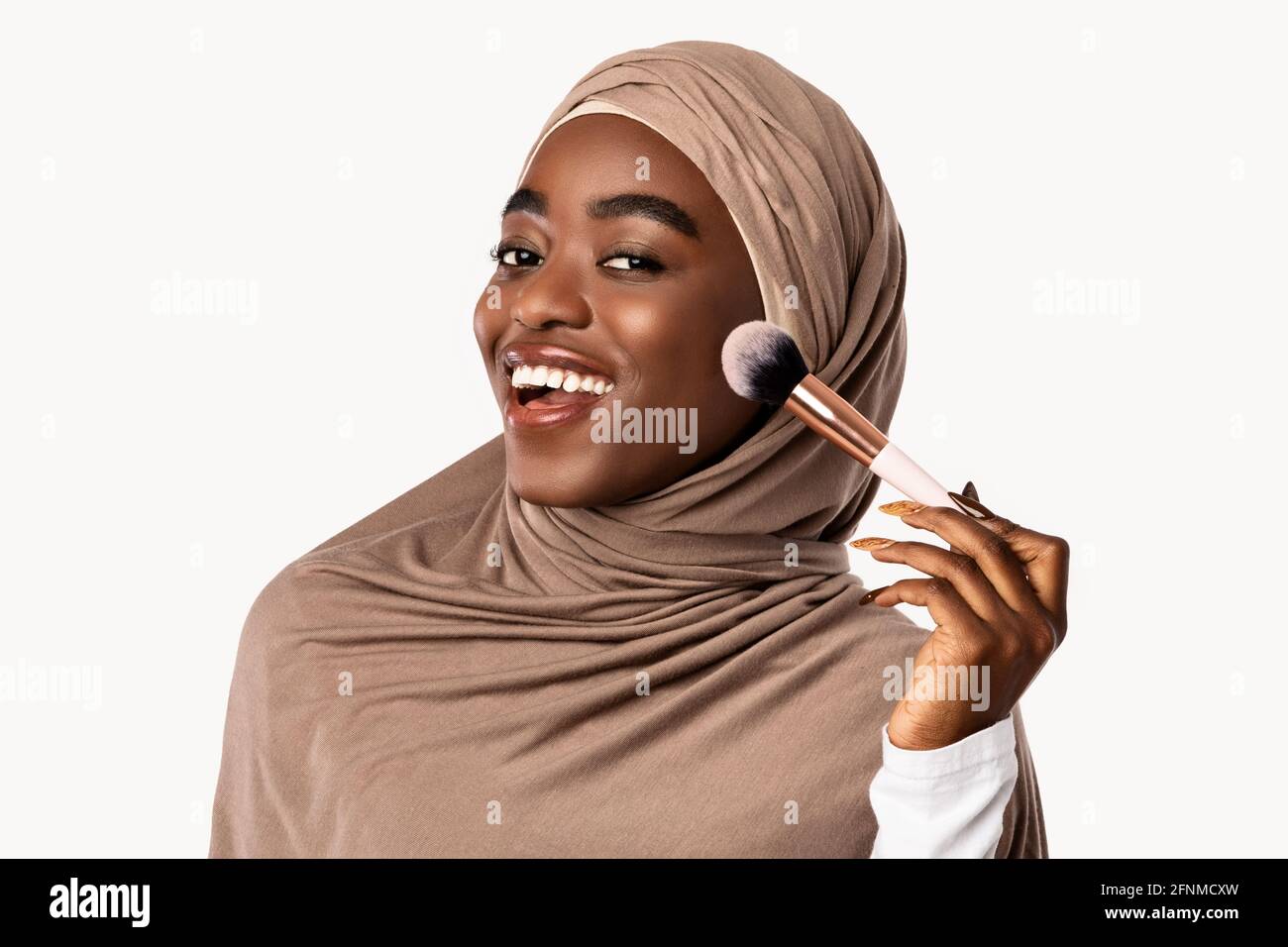 Retrato de hermosa dama musulmana negra con cepillo de maquillaje Foto de stock