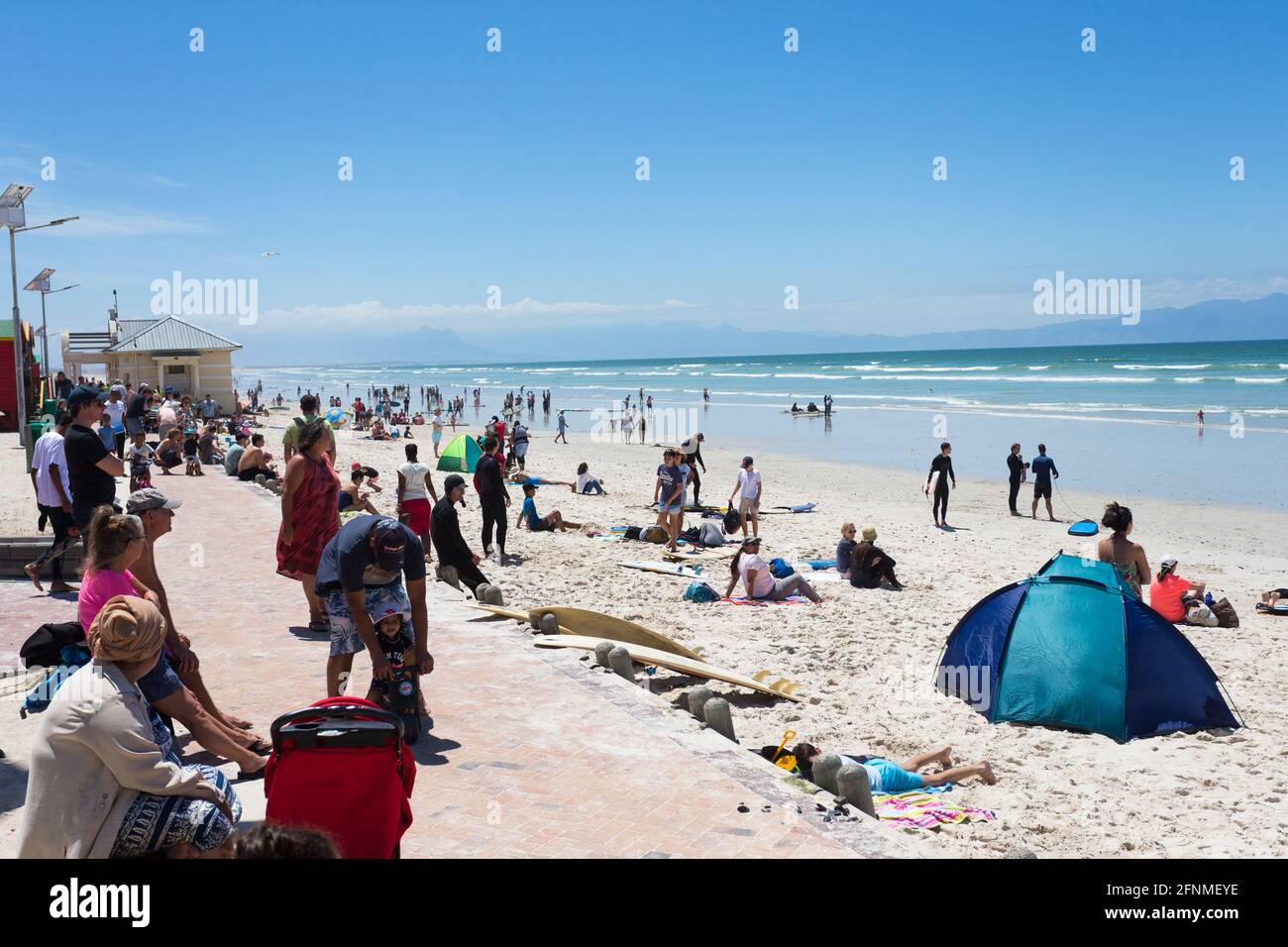 Playa de Muizenberg en un ajetreado día de verano con gente disfrutando del sol, el mar y la arena Foto de stock