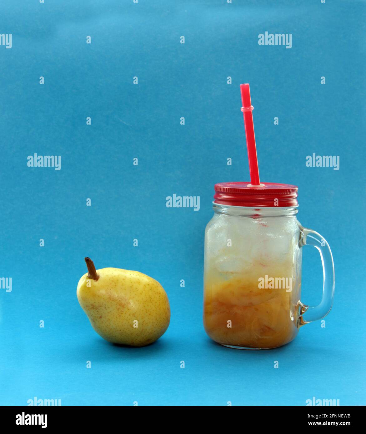 Concepto de alimentación saludable - pera y una taza de compota de pera de hielo aisladas sobre fondo azul. La imagen contiene espacio de copia Foto de stock