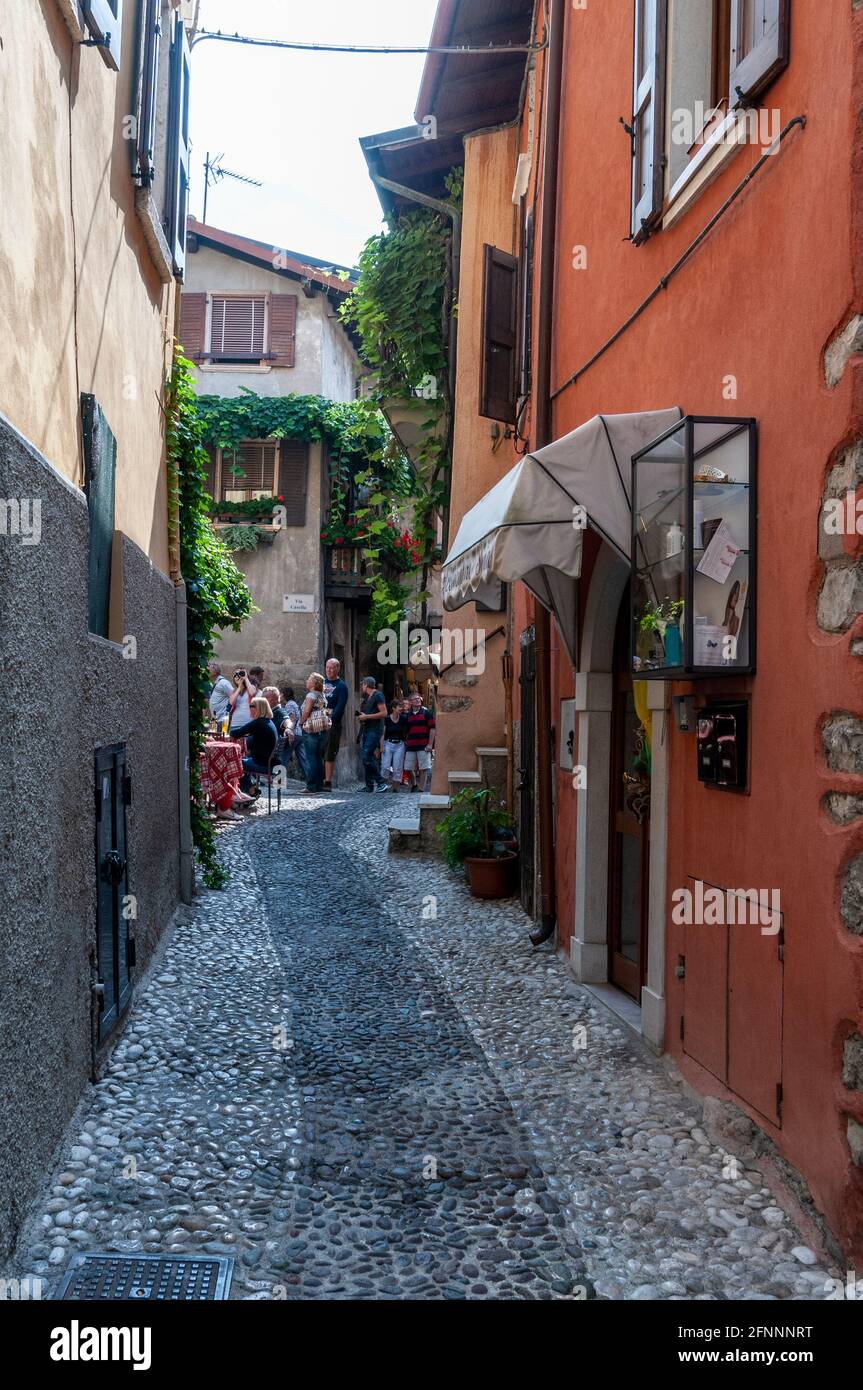 Un estrecho paso llamado Via Casella en la ciudad medieval De Malcesine en la orilla oriental del Lago de Garda en Región del Véneto, al norte de Italia Foto de stock