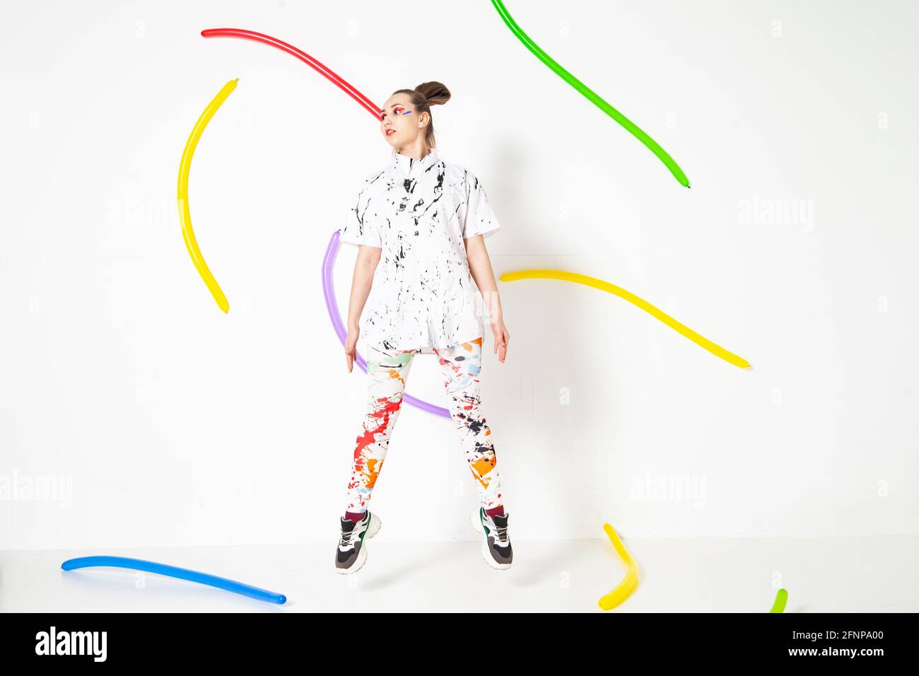 Vista lateral de la mujer que lleva ropa manchada con pintura colorida manchas de pie sobre fondo blanco en estudio globos largos Fotografía de stock - Alamy
