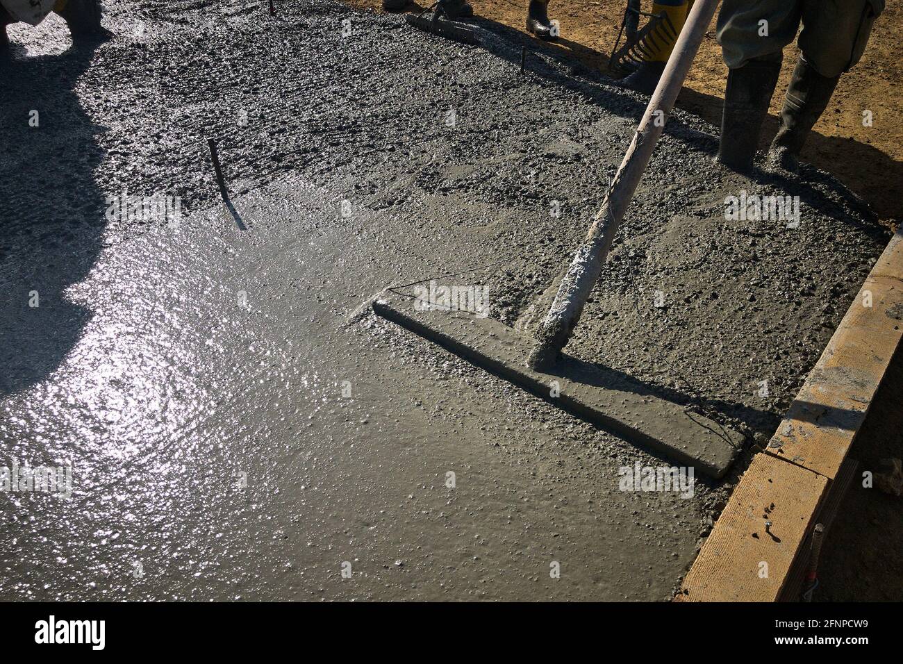 Los trabajadores de la construcción nivelan hormigón recién fundido con  flotador de toro Fotografía de stock - Alamy