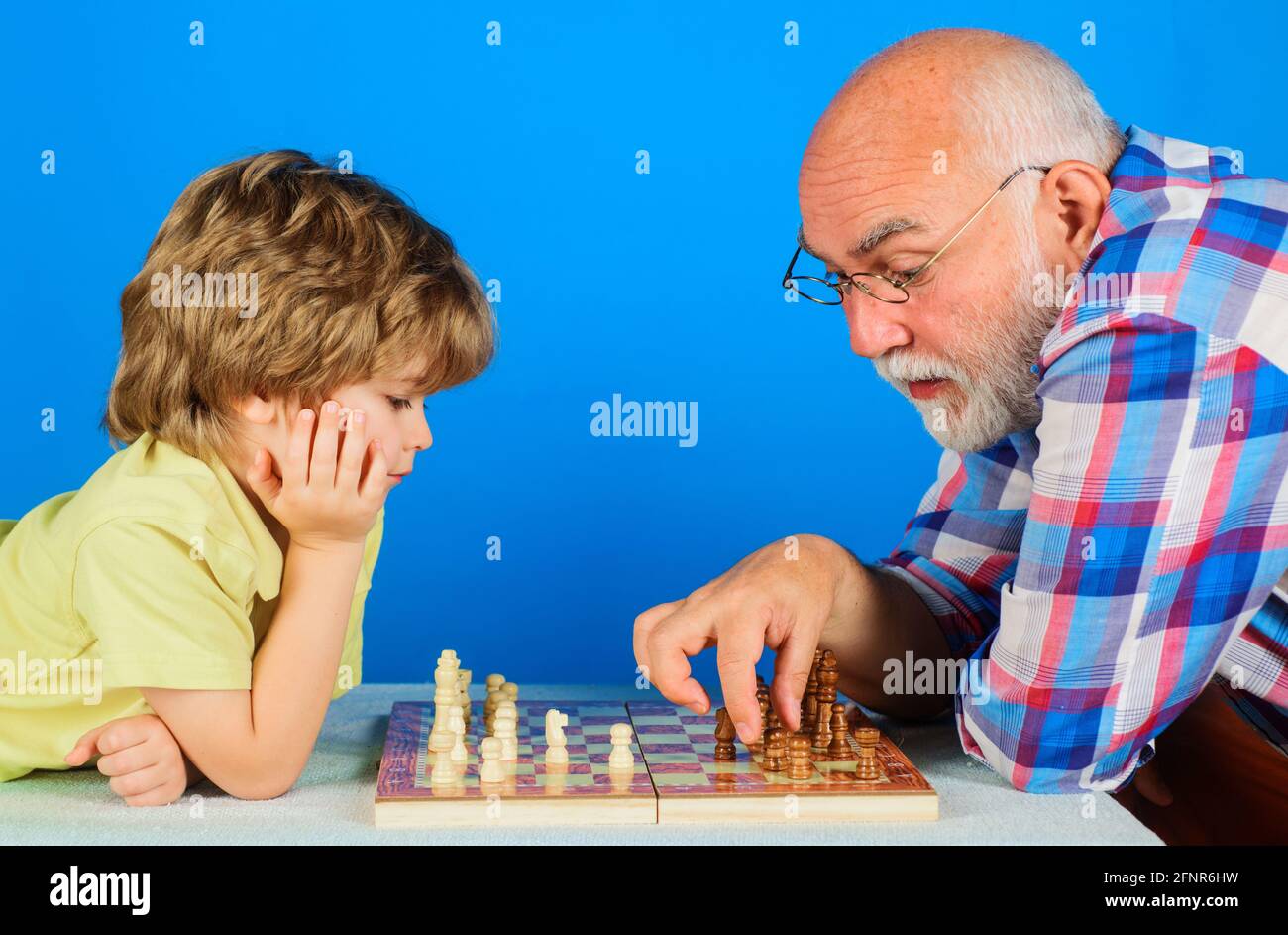 Nieto jugando ajedrez con abuelo. El abuelo que enseña a los nietos a jugar ajedrez. Relación familiar. Foto de stock