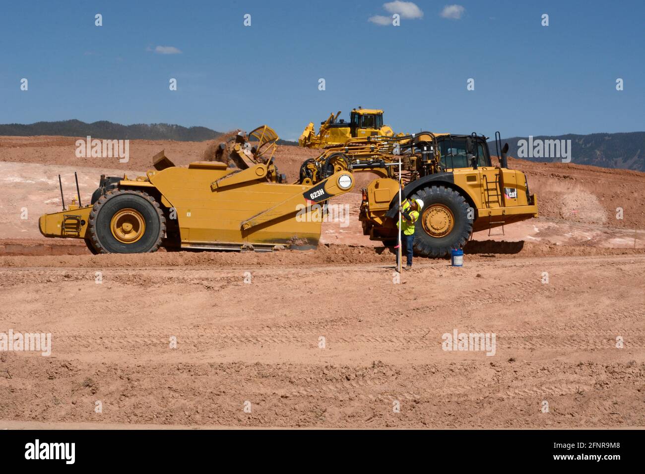 Un operador de equipo pesado utiliza una rasqueta de tractor de ruedas  Caterpillar 623H para eliminar la suciedad en el lugar de trabajo de mejora  de carreteras en Santa Fe, Nuevo México