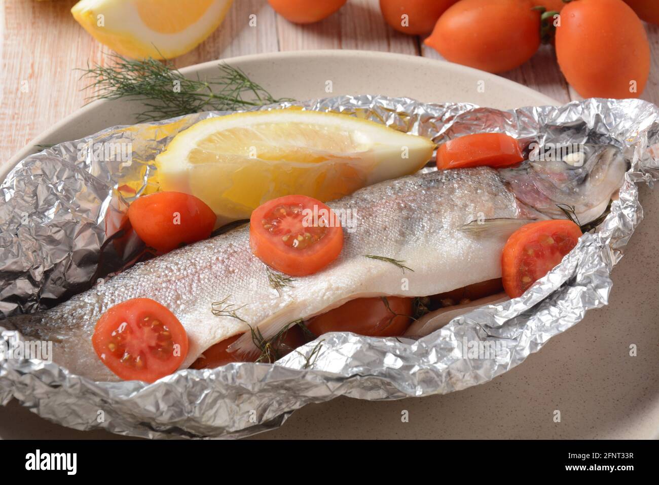 Trucha de horno perfectamente cocida con limón y eneldo con tomates cherry,  aceite de oliva, jugo de limón en papel de aluminio Fotografía de stock -  Alamy