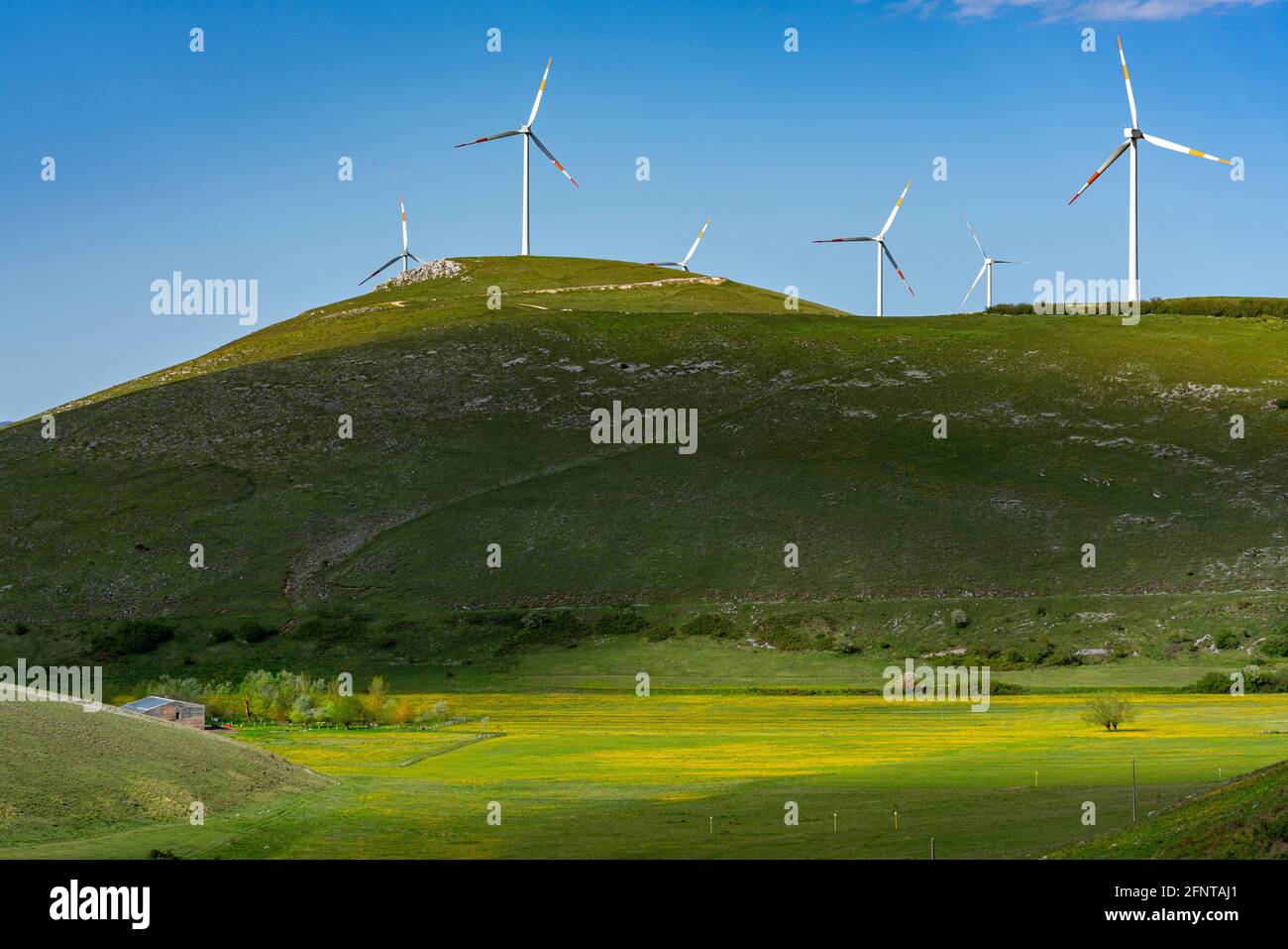Panorama de campos verdes y amarillos con colinas y aerogeneradores en la parte superior. Juego de luz y sombra. Abruzzo, Italia, Europa Foto de stock
