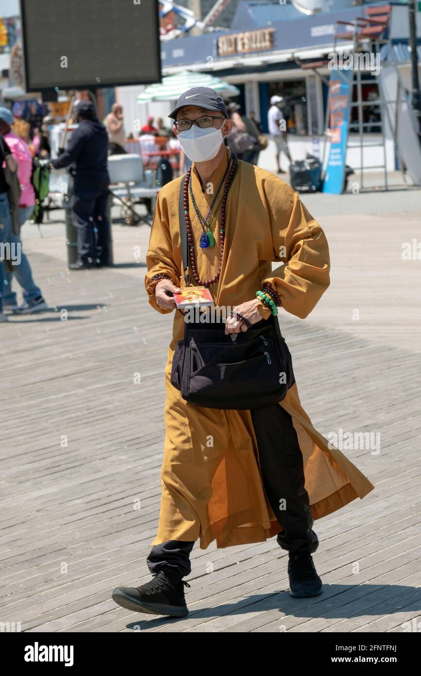 Un hombre que afirma ser budista, ofrece libros y pulseras y pide donaciones. En el paseo marítimo en Coney Island, Brooklyn, Nueva York. Foto de stock