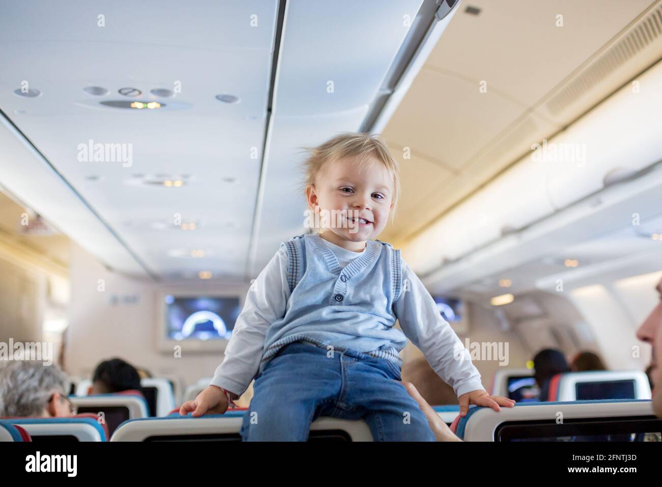 Padre, entreteniendo al niño pequeño a bordo de un avión en un vuelo internacional de larga distancia, mientras viaja a unas vacaciones Foto de stock