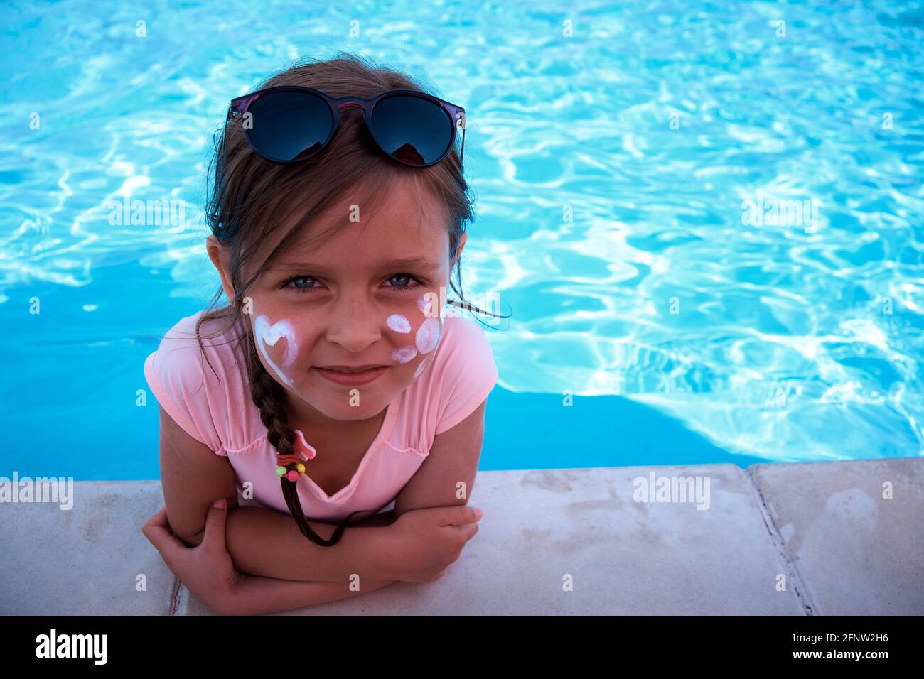 Una chica linda al lado de la piscina con el sol de la crema en su mejilla.  Protección UV con protector solar. SPF Creame ad Fotografía de stock - Alamy