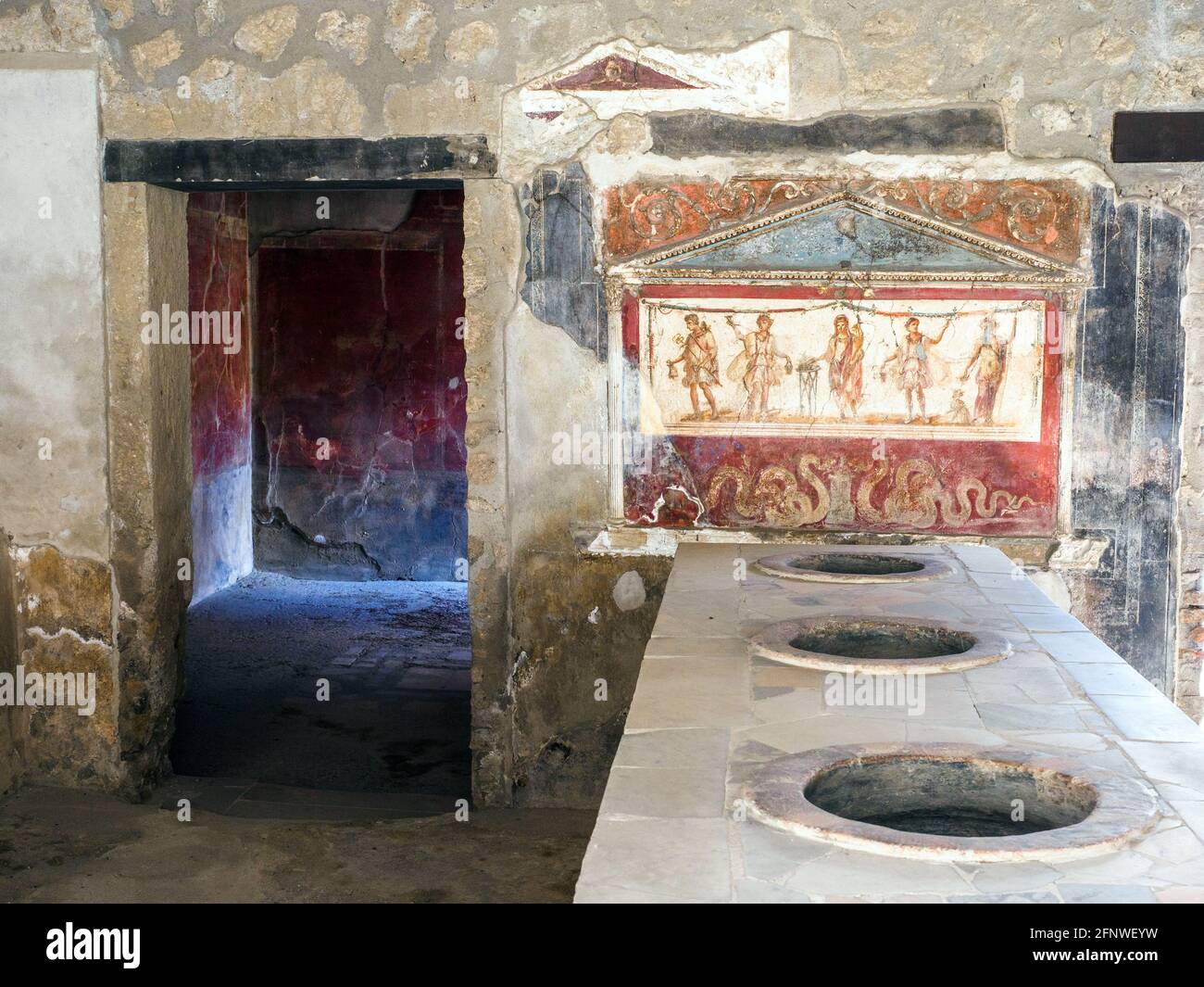 La zona del bar sirve comida y bebida. El mostrador de mármol tiene tarros en la encimera que se utilizaban para guardar la comida. Casa e Thermopolium di Vetutius Placidus (Termopolio y casa de Vetutius Placidus) - Sitio arqueológico de Pompeya, Italia Foto de stock