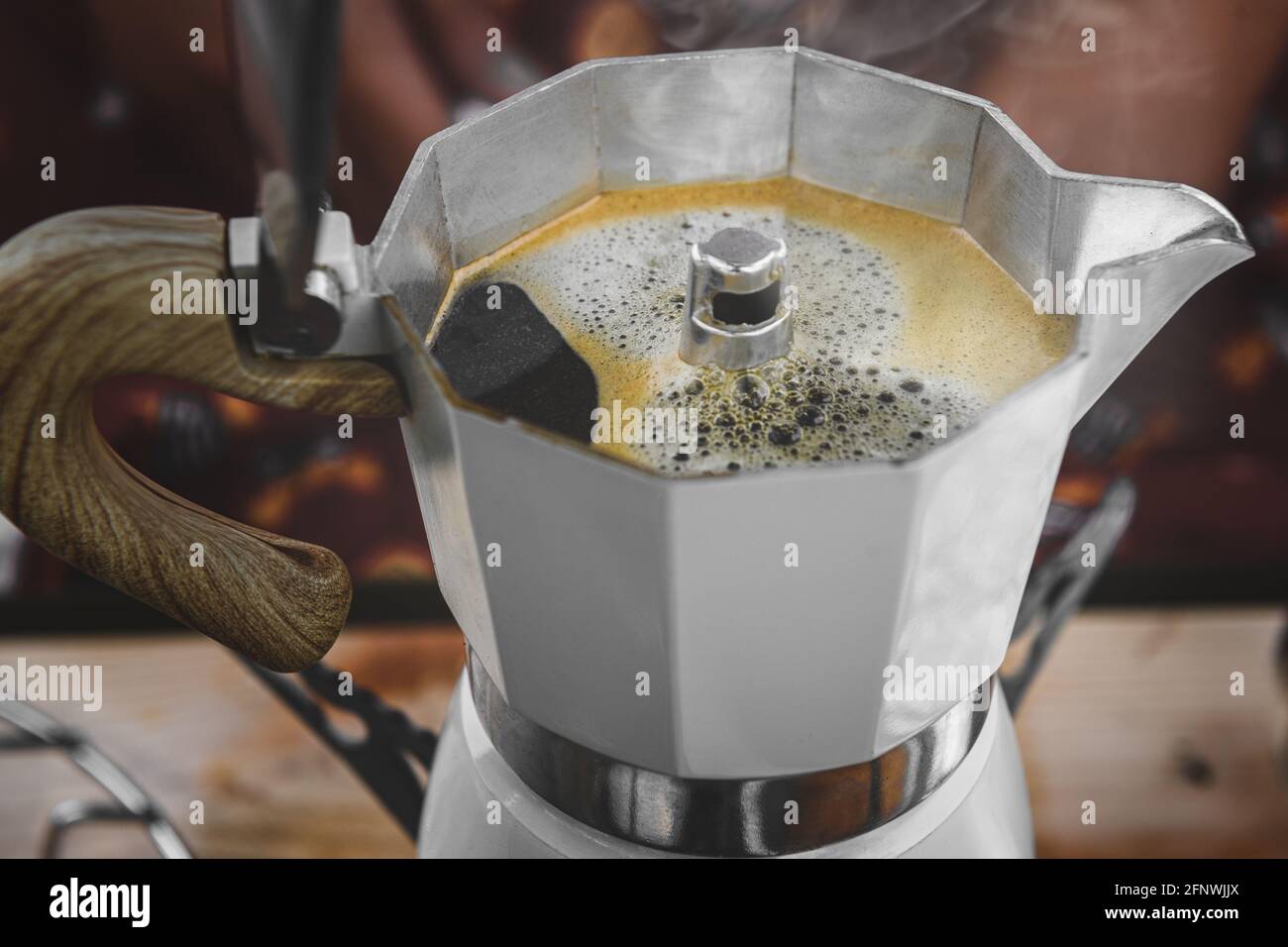 Cafetera italiana de moca sobre la estufa humeando vapor y aroma