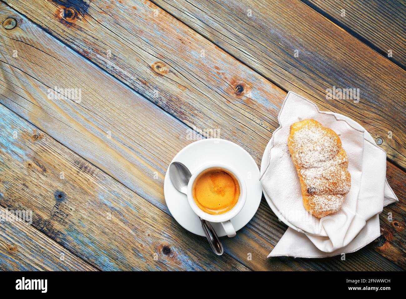Vista desde arriba. Taza de café espresso italiano caliente y cruasanes sobre un fondo de madera rústica azul claro. Comida y bebida. Estilo de vida. Foto de stock
