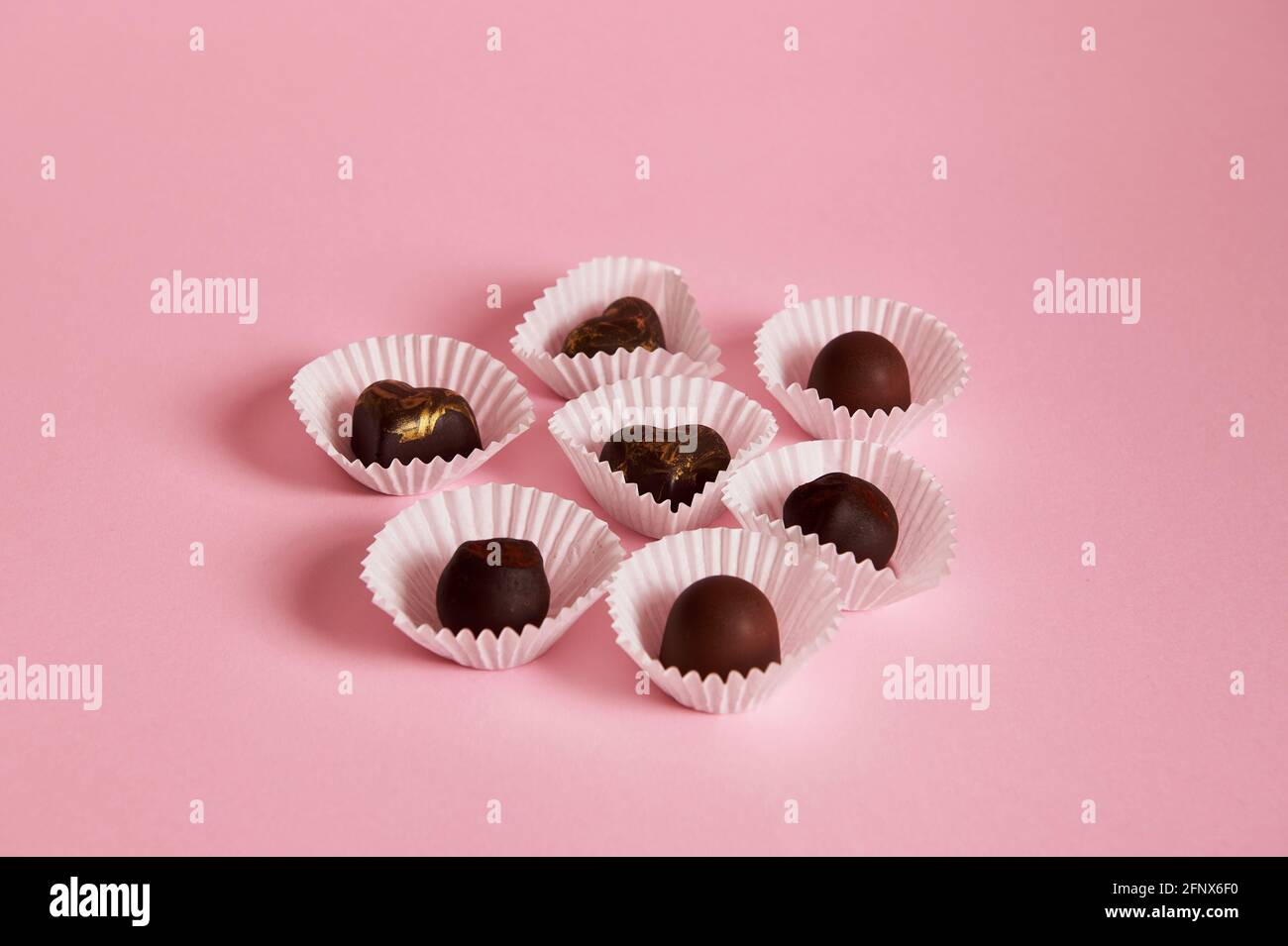 Composición de trufas de chocolate y pralinés en envolturas de papel sobre  fondo rosa con espacio de copia. Concepto de día de chocolate Fotografía de  stock - Alamy