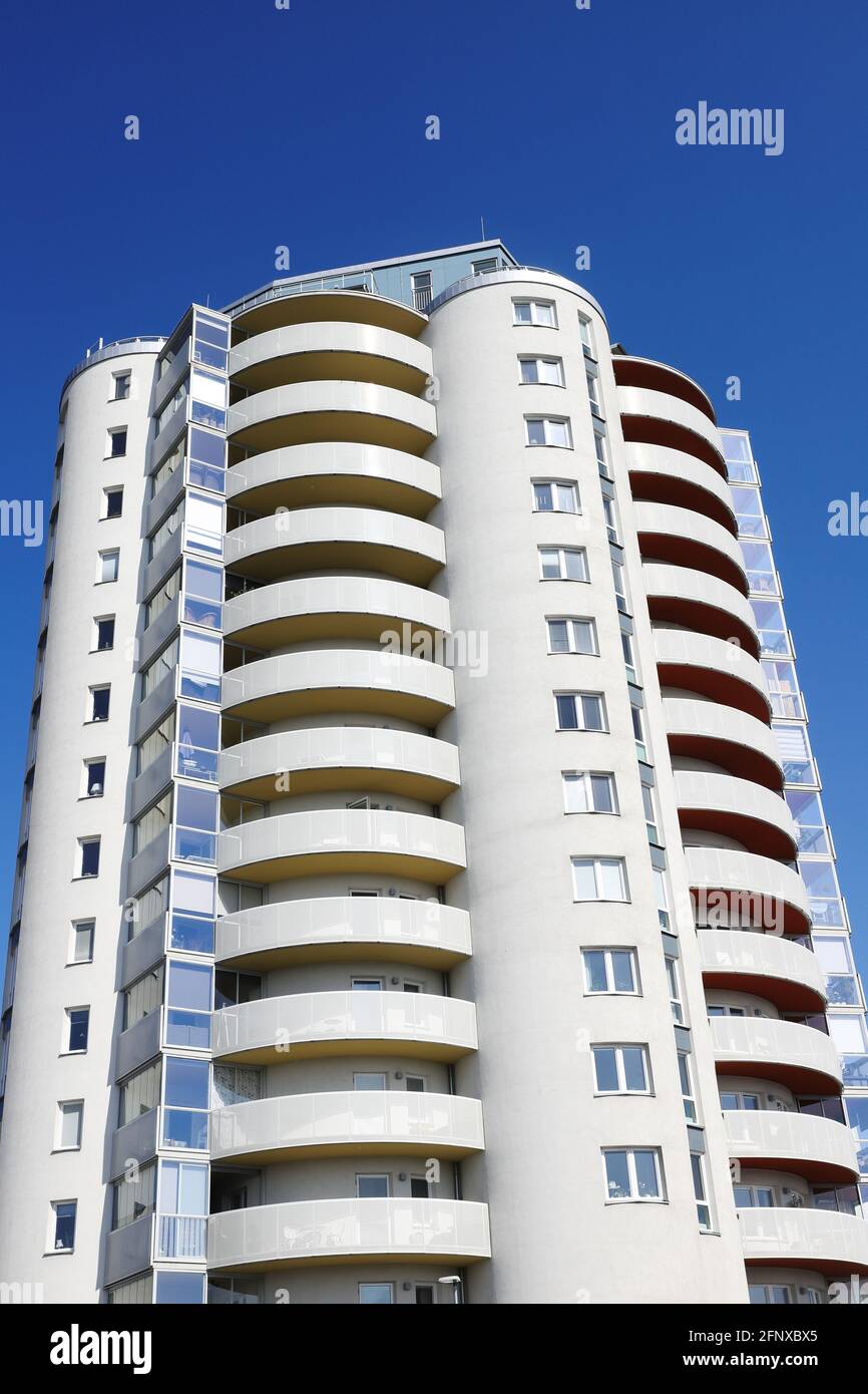 Vista en ángulo bajo de un edificio de apartamentos residenciales de gran altura, de color gris, con balcones redondos. Foto de stock