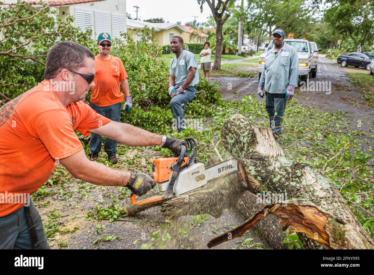 Miami Florida,Coral Gables Huracán Katrina daño,trabajadores de la ciudad aserrando árboles caídos sierra portátil,hombres hispanos negros, Foto de stock