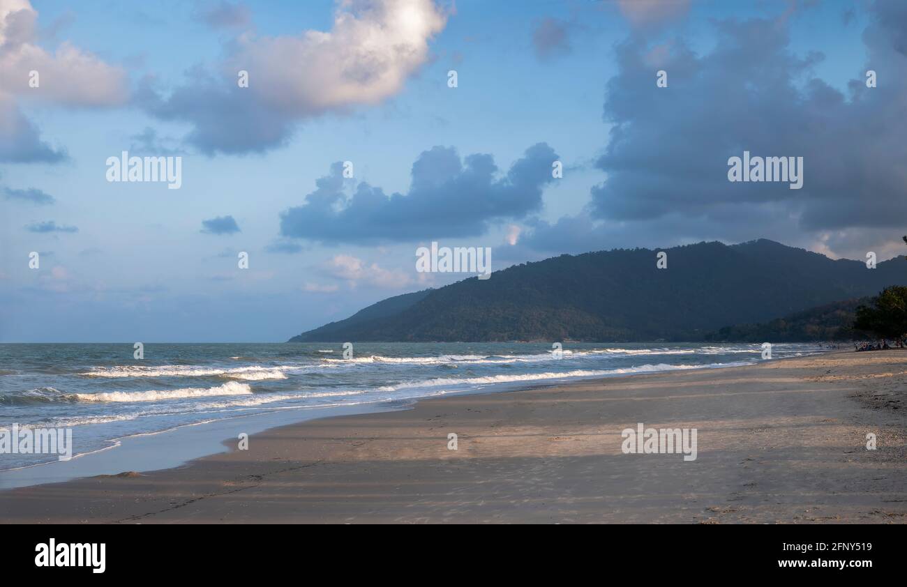 Calmful Ocean Beach puesta de sol con montaña, cielo azul brillante y olas ventosas en Kanom, Tailandia Foto de stock