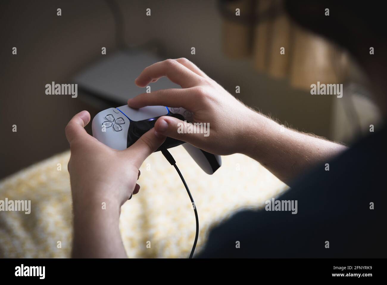 YORK, REINO UNIDO - 9 DE MAYO DE 2021. Primer plano de un adolescente sosteniendo un controlador de consola de juegos PS5 y usando el joypad con sus dedos Foto de stock