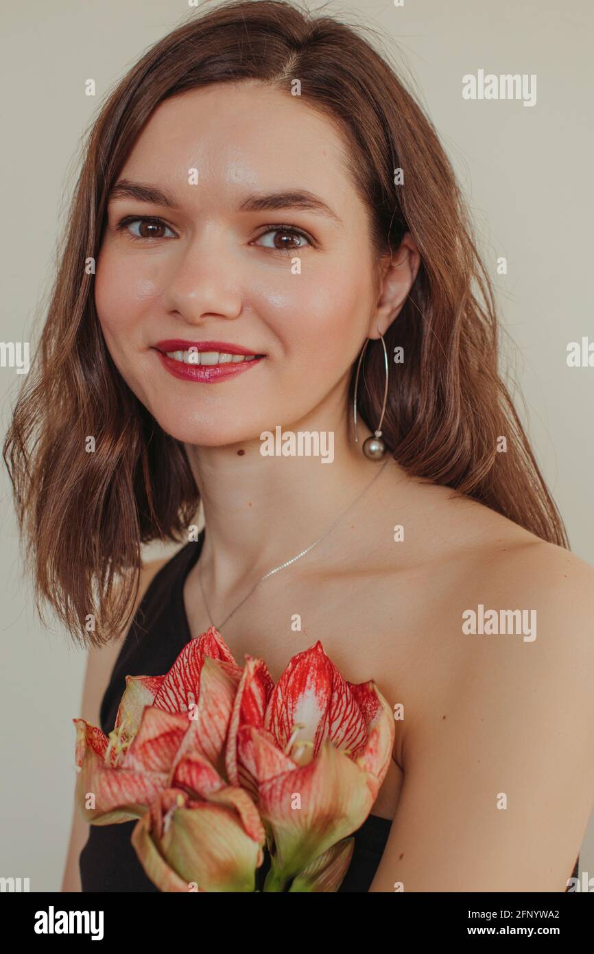 Retrato de una hermosa mujer sonriente sosteniendo una flor de amaryllis Foto de stock