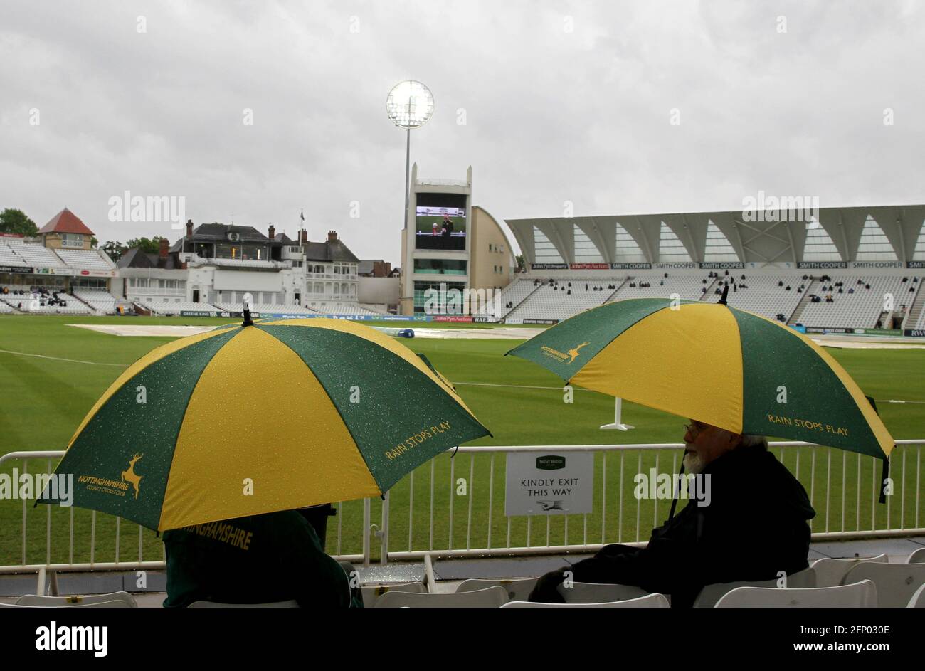 Los espectadores se refugian bajo las sombrillas de Nottinghamshire, ya que las paradas de lluvia juegan durante el primer día del VI= Campeonato del Condado de Seguros en Trent Bridge, Nottingham. Fecha de la foto: Jueves 20 de mayo de 2021. Foto de stock