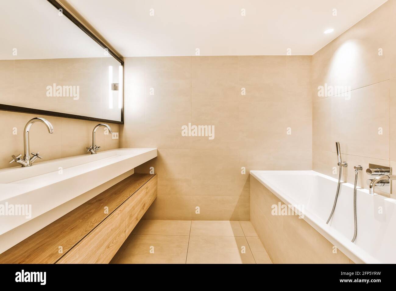 Paredes de azulejos beige en el baño con lavabo doble blanco debajo espejo  opuesto a la bañera blanca con grifo de montaje en pared Fotografía de  stock - Alamy