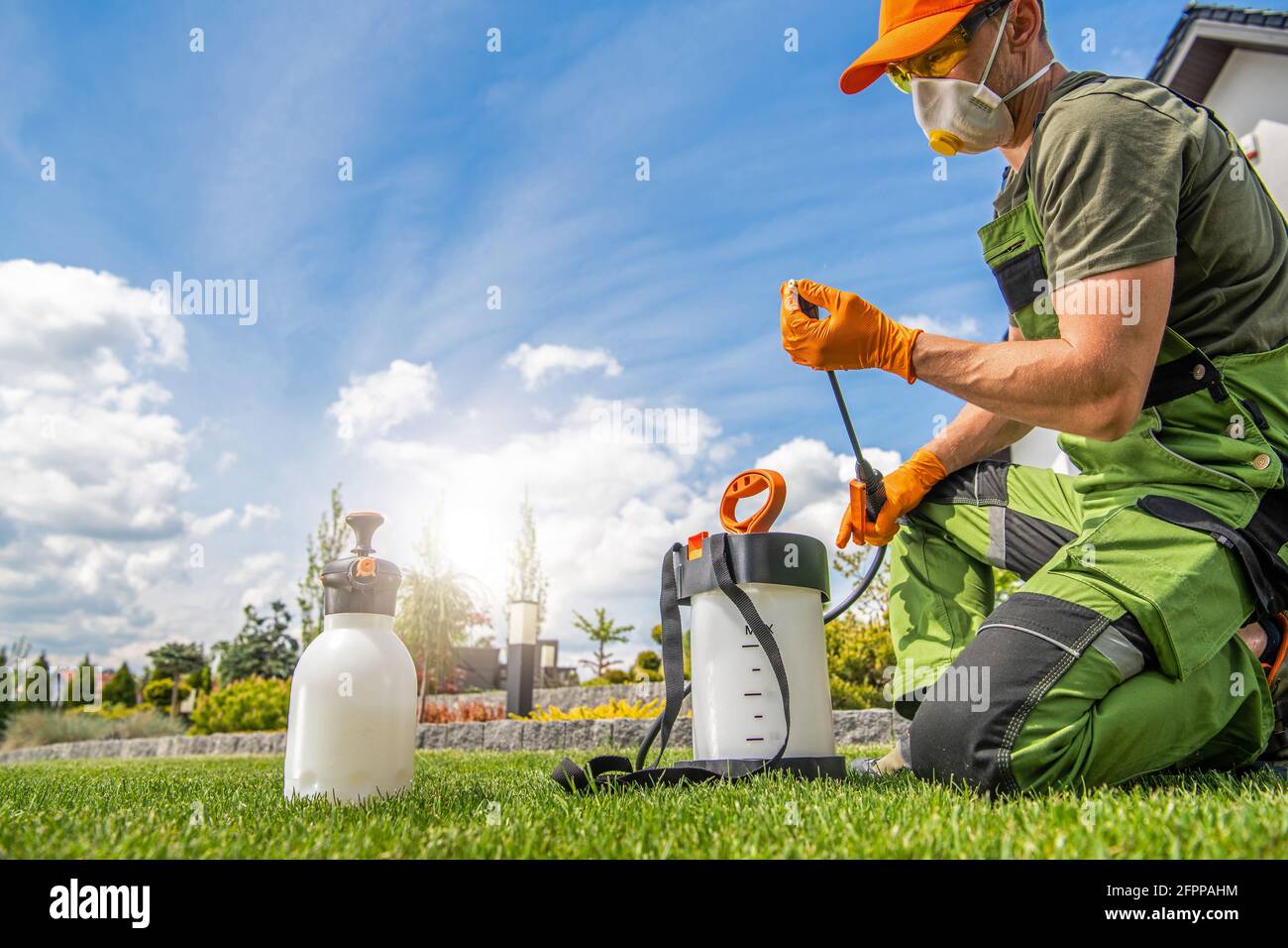 Trabajador caucásico en su 40s Preparación del equipo de pulverización para el control de plagas. Tema de mantenimiento del jardín de primavera. Foto de stock