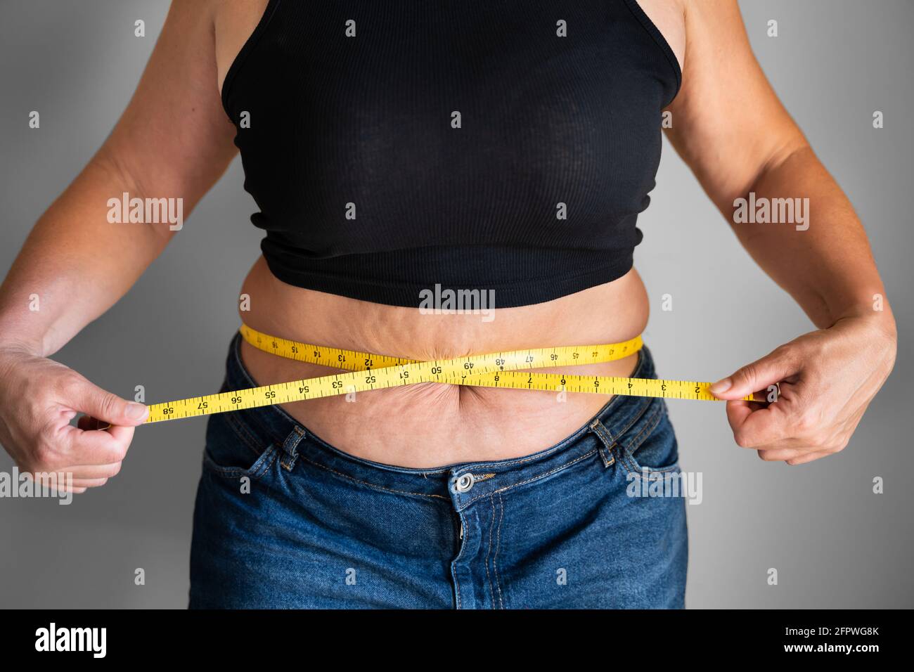Mujer caucásica con grasa de vientre usando cinta Medir primer plano Foto de stock