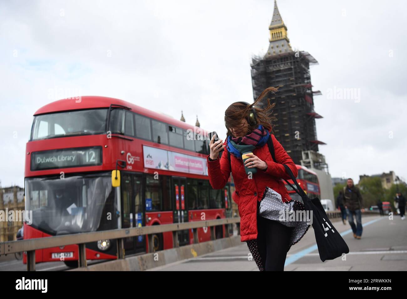 Una mujer golpeada por el viento mientras cruzaba el puente de Westminster, Londres, con previsión de viento y lluvia para hacer estragos en el Reino Unido el primer viernes que se ha permitido a la gente reunirse en grandes grupos fuera de Inglaterra. Fecha de la foto: Viernes 21 de mayo de 2021. Foto de stock