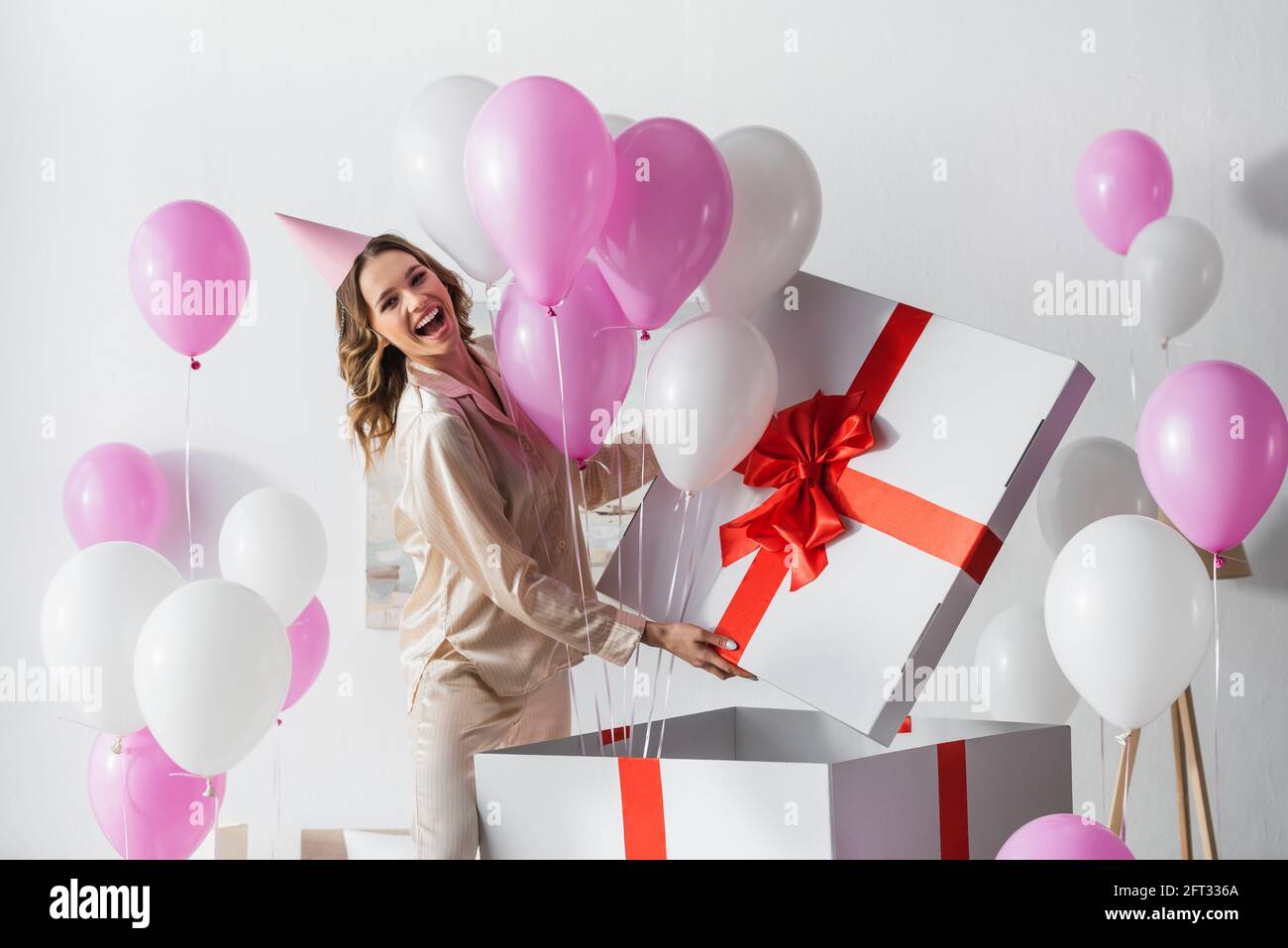 Mujer positiva de pie cerca de una caja de regalo grande con globos durante  celebración de cumpleaños en casa Fotografía de stock - Alamy