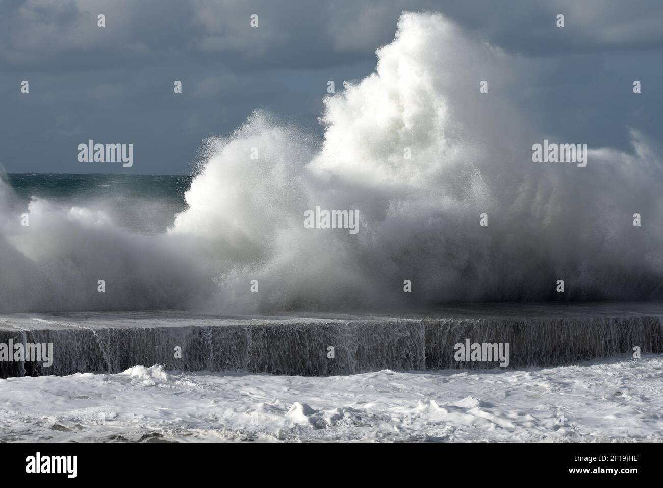Rotura de la ola en un pastel de piedra rin un invierno tormentoso día/ Foto de stock