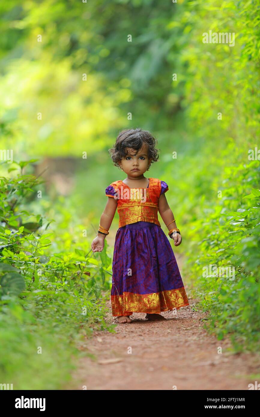 South Indian linda niña niño vestido tradicional hermoso falda larga y blusa,  caminar a través de la manera del pueblo con fondo verde Fotografía de  stock - Alamy