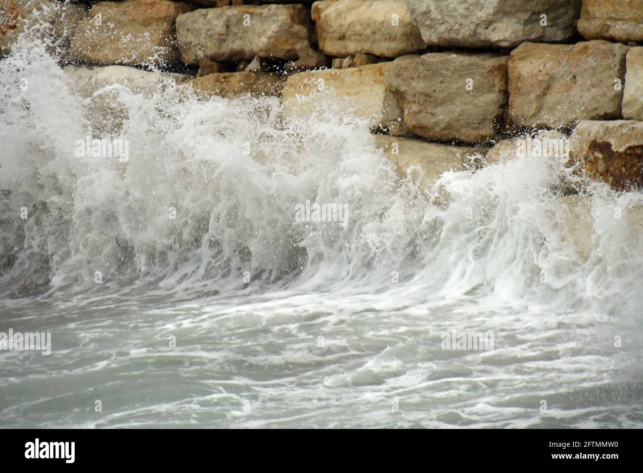 rotura de la onda en la pared de piedra Foto de stock