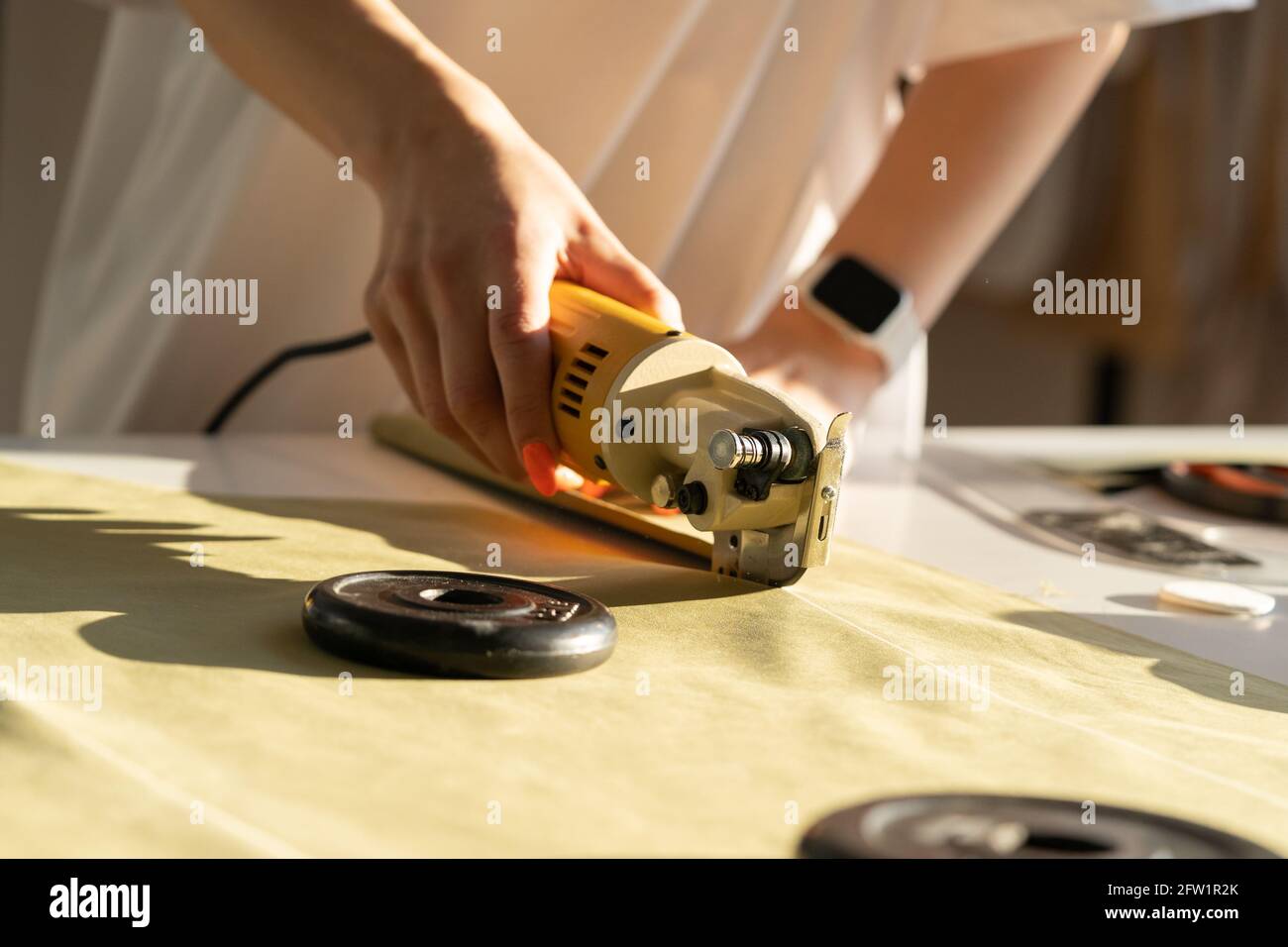 Diseñador Utilice un cortador eléctrico para cortar el trabajo de tela en  el estudio. Primer plano de tela a medida para coser Fotografía de stock -  Alamy
