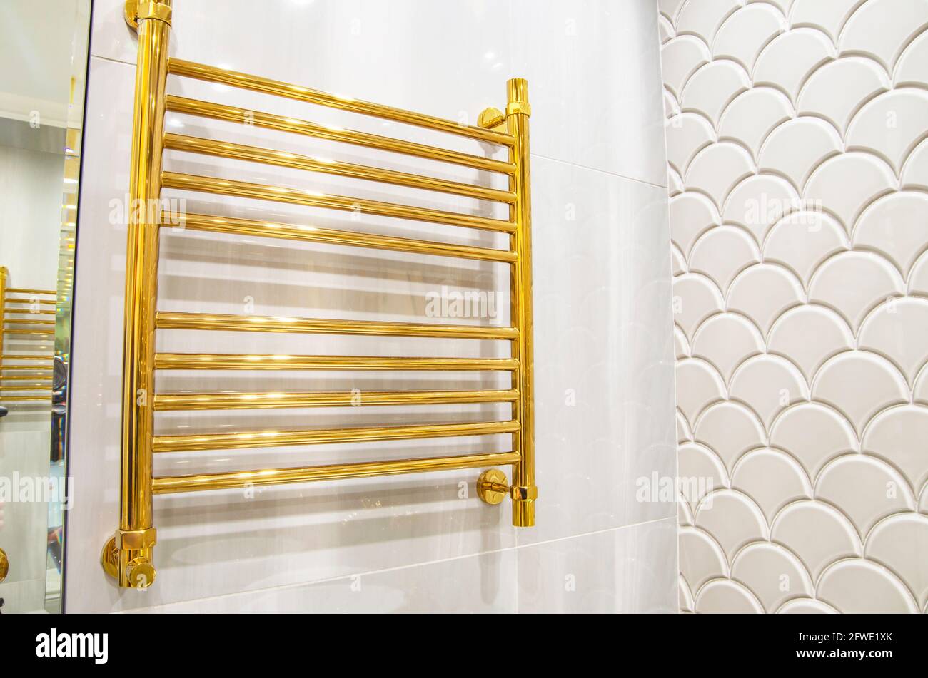 Toallero dorado calentado en una pared blanca, luz cálida. Pared del baño  Fotografía de stock - Alamy