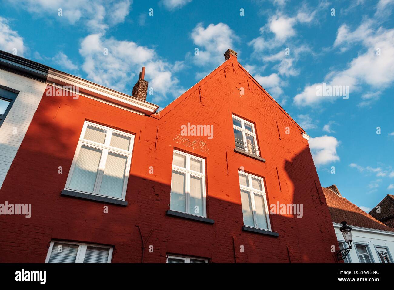 Primer plano de una fachada de color rojo vibrante hecha de ladrillos contra el cielo azul en Brujas, Bélgica. Foto de stock