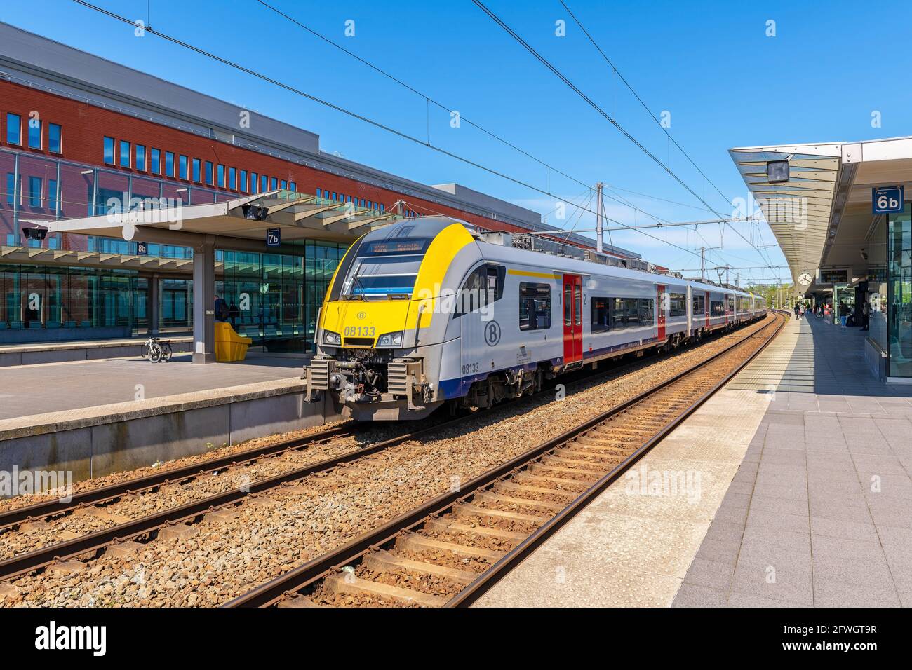 Locomotora de tren con vagones en la estación de tren de Brujas con vías y plataformas, Bélgica. Foto de stock