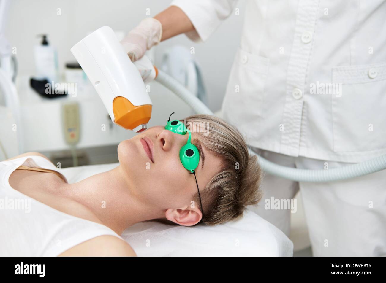 Primer plano de una mujer joven en gafas protectoras con láser UV que  reciben tratamiento con láser en la cara en el centro SPA contemporáneo.  Cuidado facial de la piel. ipl de