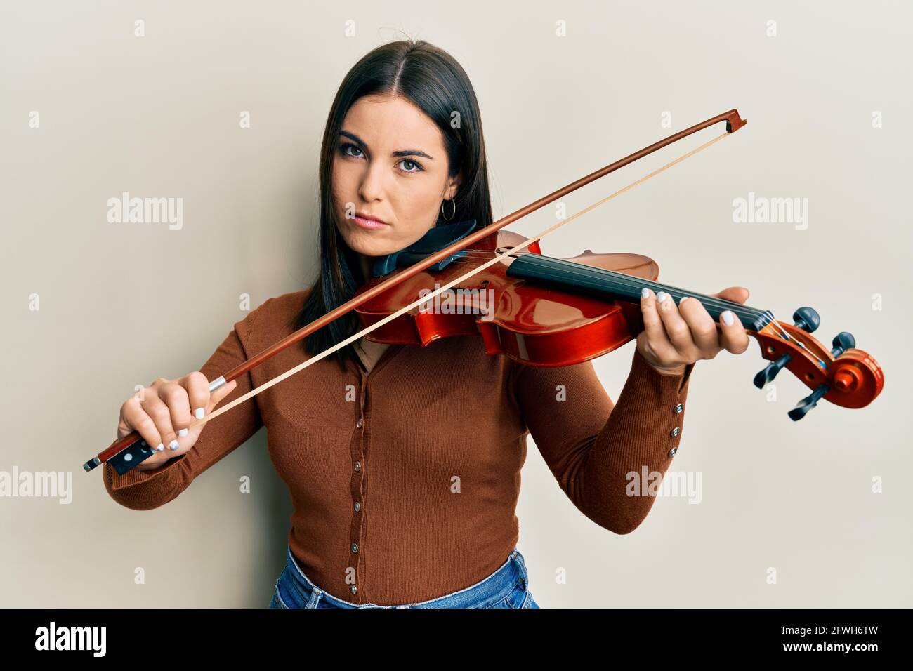 Hospitalidad cuenta libertad Joven mujer morena tocando violín escéptica y nerviosa, retocada por  problema. Persona negativa Fotografía de stock - Alamy