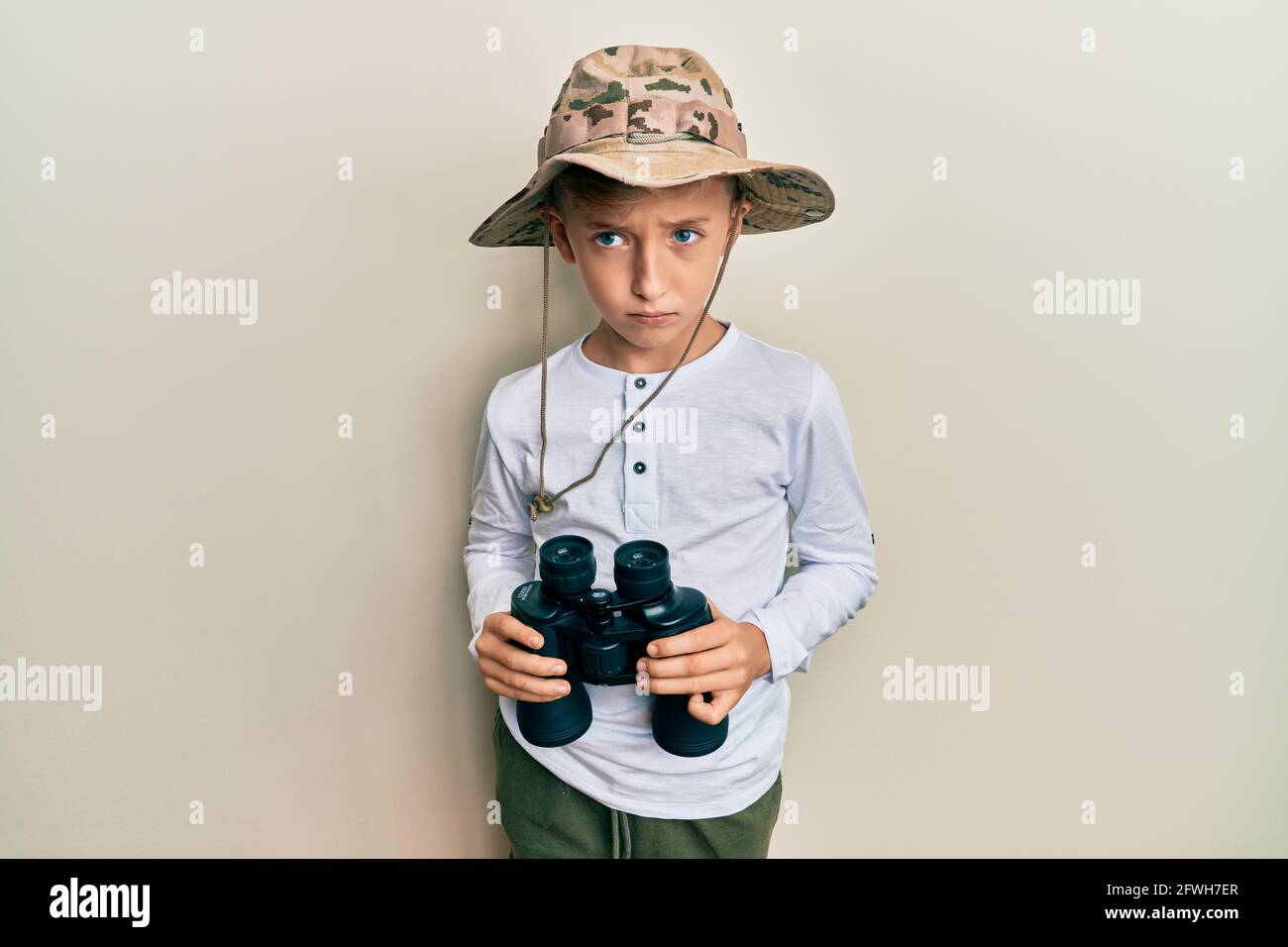 Niño pequeño caucásico con sombrero explorador sosteniendo prismáticos  escépticos y nerviosos, frunciendo el ceño molesto por problema. Persona  negativa Fotografía de stock - Alamy