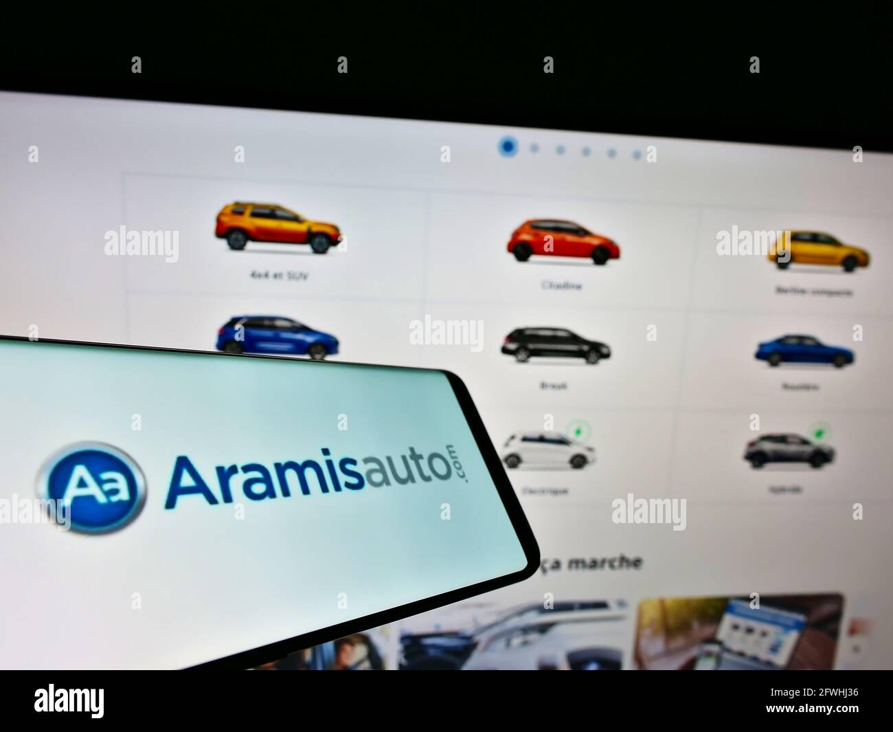 Teléfono móvil con el logotipo del distribuidor de coches en línea francés Aramis SAS (Aramisauto) en la pantalla frente al sitio web. Enfoque en la pantalla central derecha del teléfono. Foto de stock