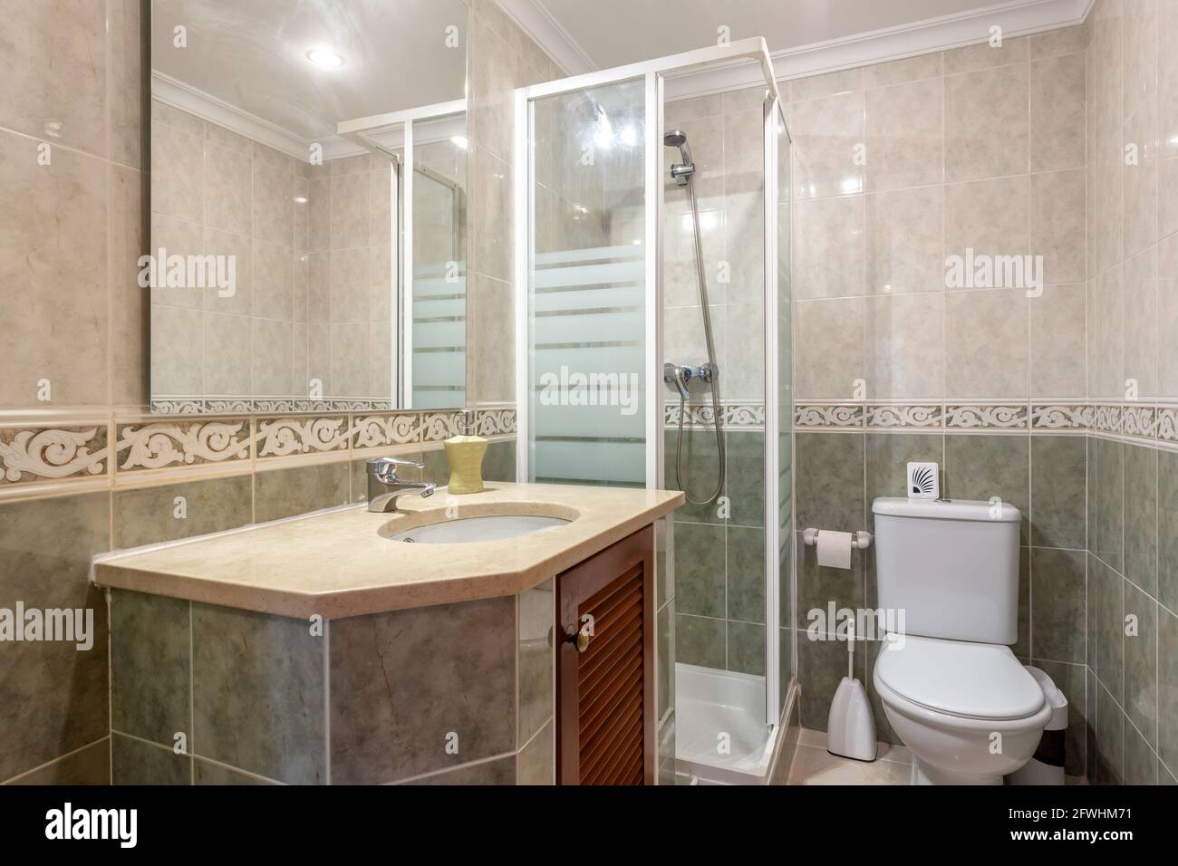 Baño sencillo de temática beige decorado con algunas toallas limpias. Hay  un lavabo moderno al lado de una ducha, iluminado por una ventana hacia el  exterior Fotografía de stock - Alamy