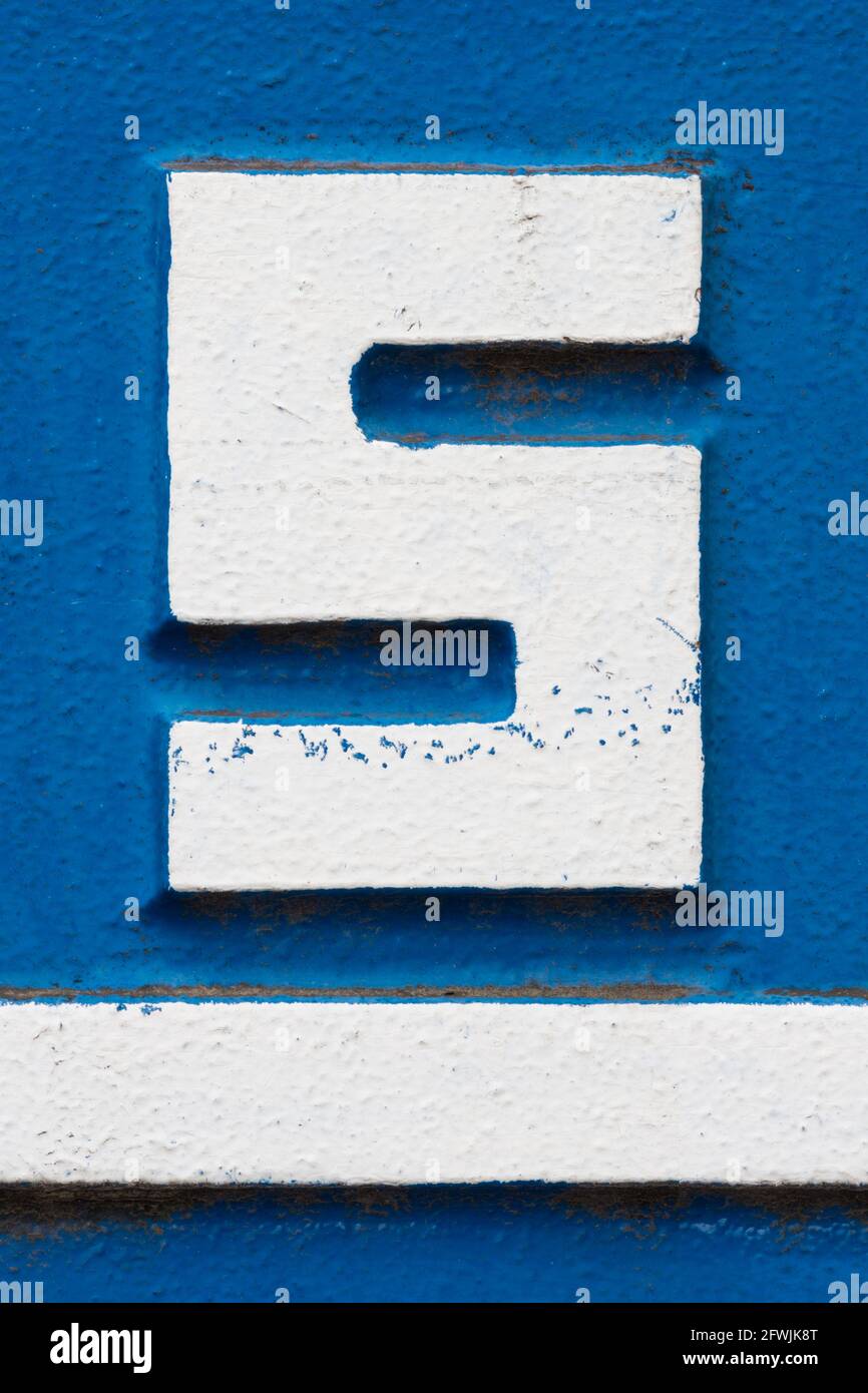 Letra S de metal blanco con subrayado blanco sobre fondo azul Foto de stock