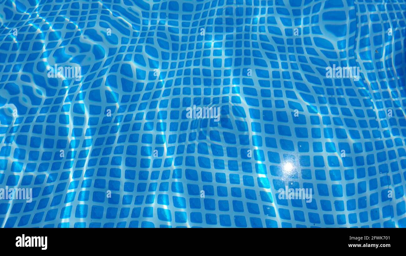Textura de la superficie del agua con olas y ondulaciones limpias en la piscina. Refracción de la textura de la vista superior de la luz del sol, el sol brilla el fondo del bucle de agua. Foto de stock