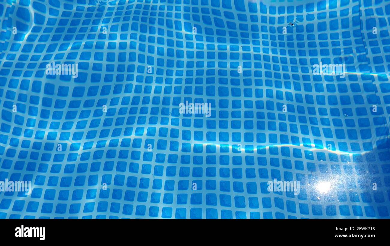 Textura de la superficie del agua con olas y ondulaciones limpias en la piscina. Refracción de la textura de la vista superior de la luz del sol, el sol brilla el fondo del bucle de agua. Foto de stock